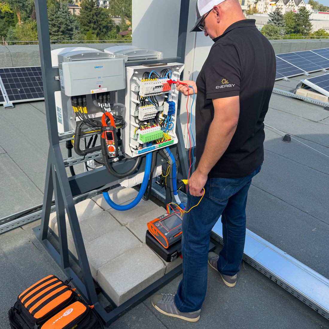 Technik OZEnergy wykonuje pomiary w rozdzielnicy instalacji PV na dachu